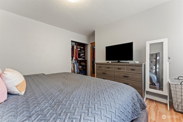 bedroom featuring a closet, light hardwood / wood-style floors, and a textured ceiling