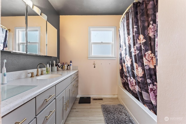 bathroom featuring hardwood / wood-style flooring, vanity, and shower / bathtub combination with curtain