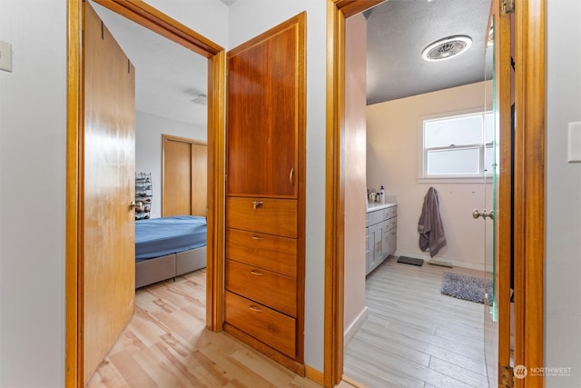 corridor with light hardwood / wood-style flooring and a textured ceiling