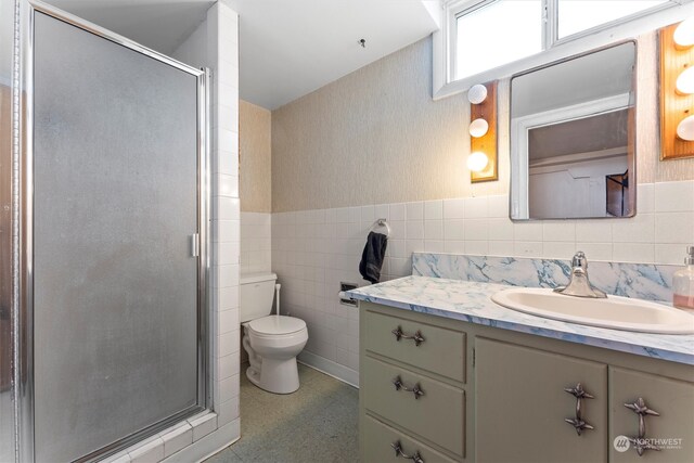 bathroom featuring an enclosed shower, tile walls, vanity, and toilet