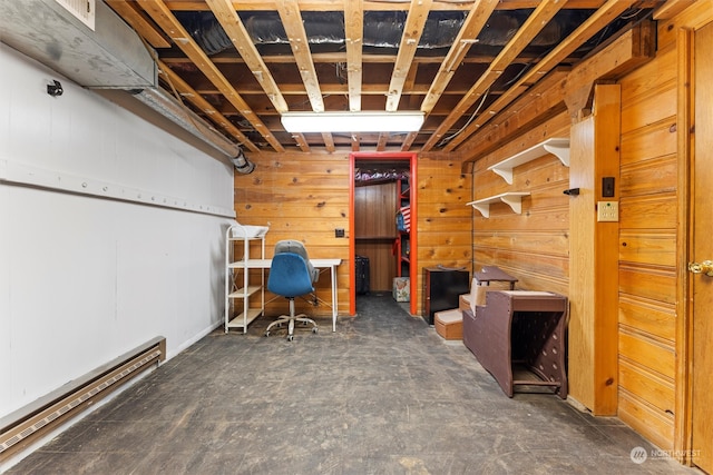 basement featuring wood walls and baseboard heating