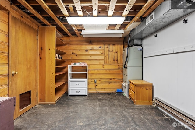 basement featuring wood walls and baseboard heating