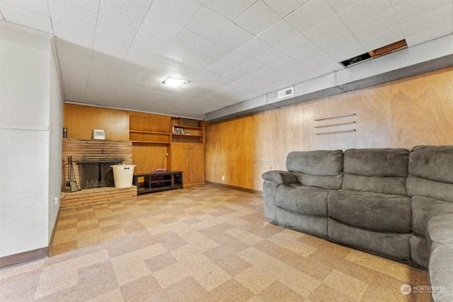 unfurnished living room featuring light carpet, wooden walls, built in shelves, and a fireplace