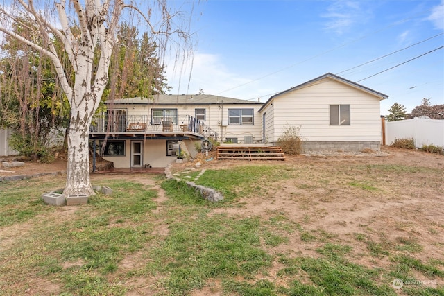 rear view of property featuring a deck and a lawn