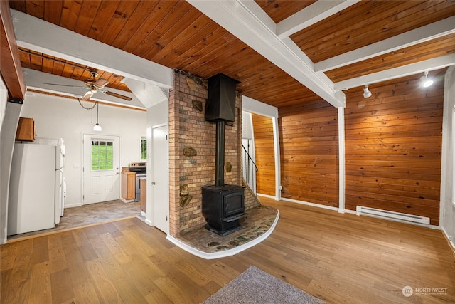 unfurnished living room with light hardwood / wood-style floors, ceiling fan, beam ceiling, baseboard heating, and a wood stove