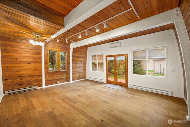 unfurnished room with light hardwood / wood-style floors, a baseboard heating unit, and wooden walls