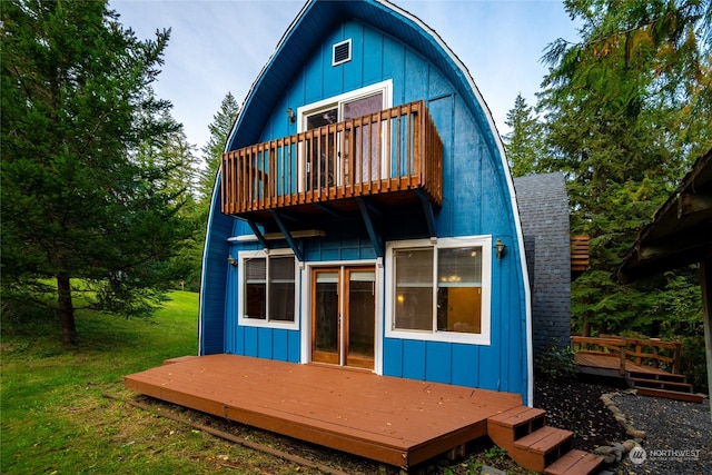 back of property with a wooden deck and a lawn