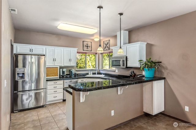 kitchen with stainless steel appliances, kitchen peninsula, hanging light fixtures, and white cabinets