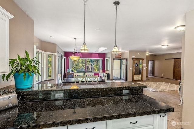 kitchen featuring white cabinets, hanging light fixtures, and a barn door