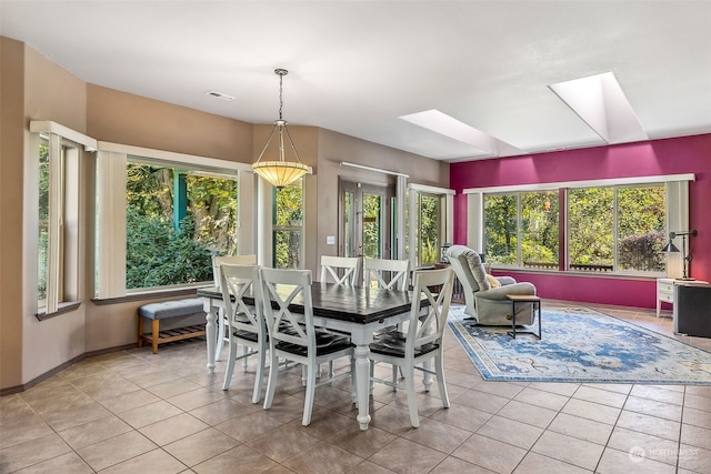 dining area featuring a skylight, light tile patterned floors, and a healthy amount of sunlight