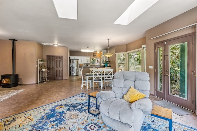 tiled living room featuring a wood stove and a skylight