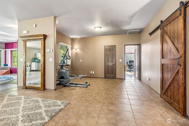 exercise room featuring a healthy amount of sunlight, a barn door, and light tile patterned floors