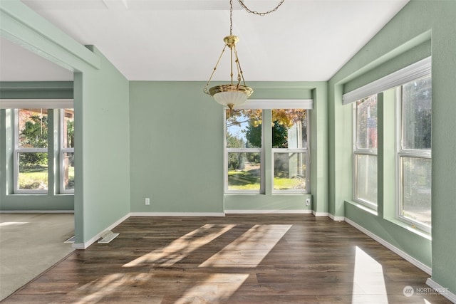 unfurnished dining area featuring lofted ceiling, dark wood-type flooring, a chandelier, and baseboards