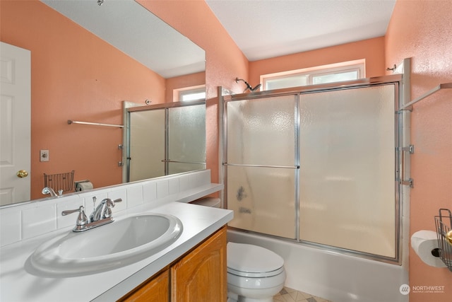 bathroom with a healthy amount of sunlight, toilet, vanity, and combined bath / shower with glass door