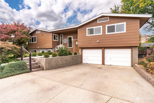 raised ranch with concrete driveway and an attached garage