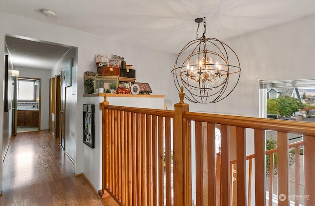 corridor with wood finished floors and a chandelier