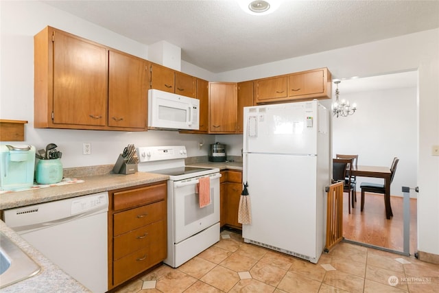 kitchen with an inviting chandelier, white appliances, a textured ceiling, and light tile patterned floors