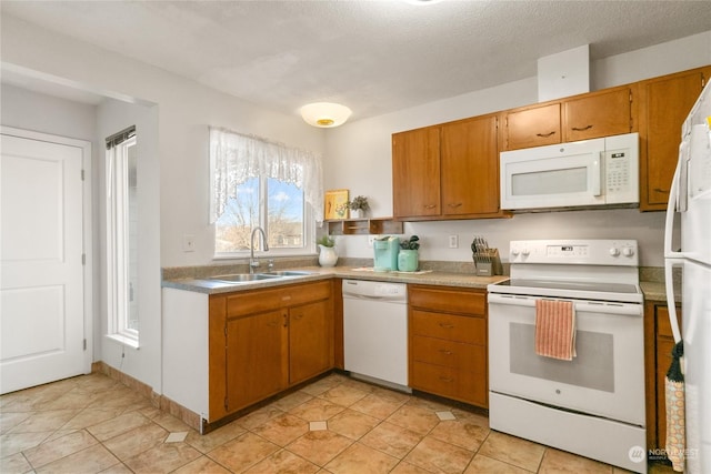 kitchen with sink, white appliances, light tile patterned floors, and a textured ceiling