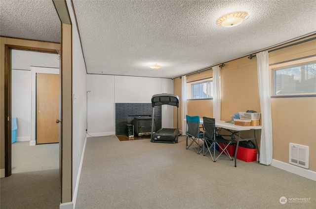 workout room with a textured ceiling, light carpet, and a wood stove