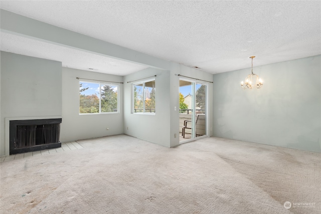 unfurnished living room featuring carpet flooring, an inviting chandelier, and plenty of natural light