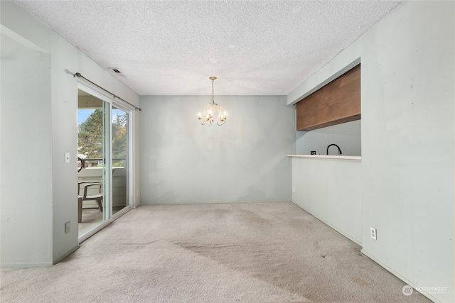 carpeted empty room featuring a textured ceiling and a chandelier