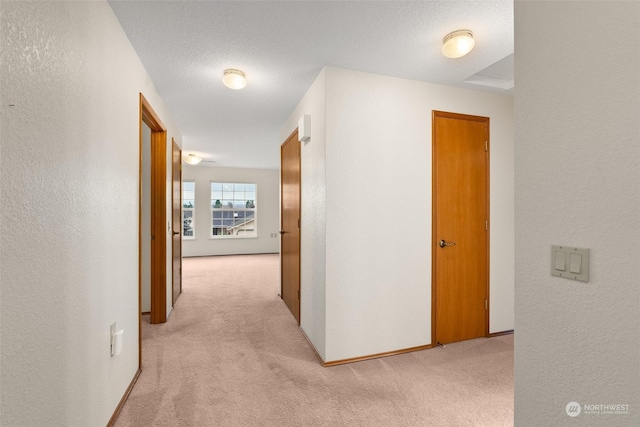 corridor featuring light colored carpet and a textured ceiling