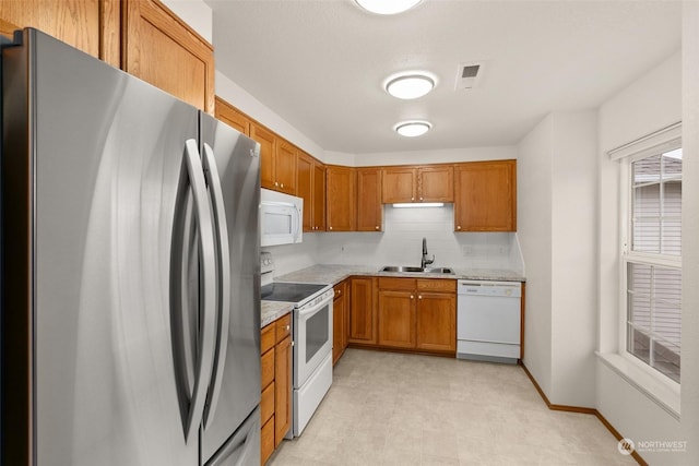 kitchen featuring decorative backsplash, sink, and white appliances