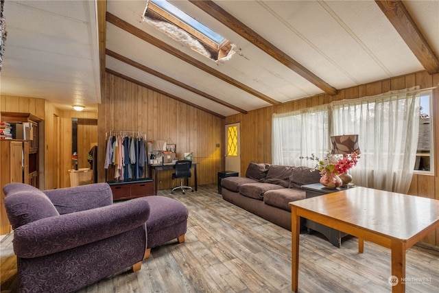 living room featuring wooden walls, hardwood / wood-style floors, and vaulted ceiling with skylight