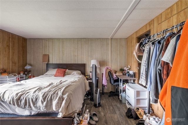 bedroom with dark hardwood / wood-style floors and wooden walls