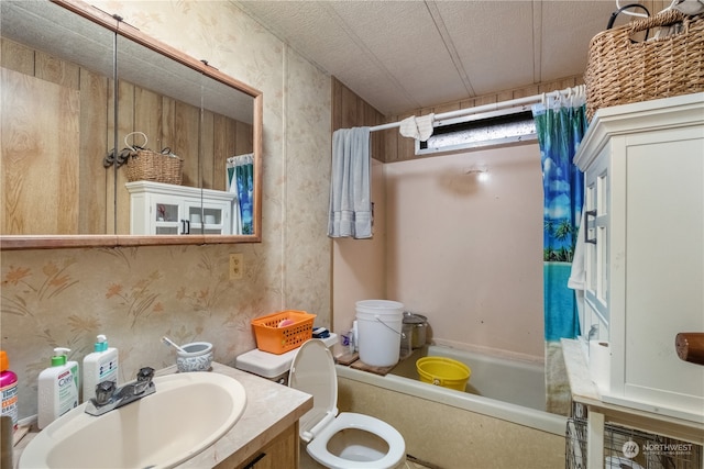 full bathroom featuring vanity, a textured ceiling, shower / bath combo with shower curtain, and toilet