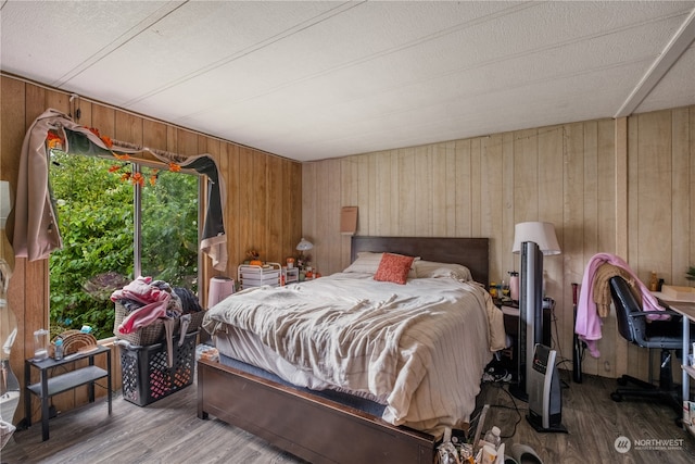 bedroom with wooden walls and hardwood / wood-style floors