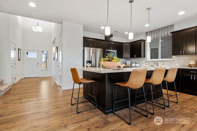 kitchen featuring a kitchen island, pendant lighting, stainless steel appliances, and light wood-type flooring