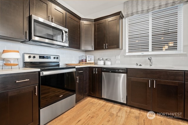 kitchen with decorative backsplash, dark brown cabinetry, light hardwood / wood-style flooring, sink, and stainless steel appliances