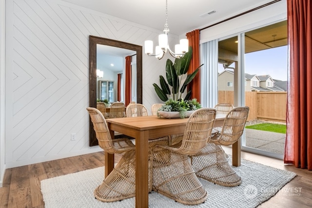 dining room featuring a notable chandelier, wood walls, and hardwood / wood-style floors