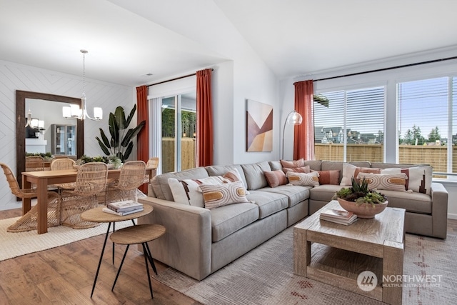 living room featuring an inviting chandelier, light wood-type flooring, and vaulted ceiling