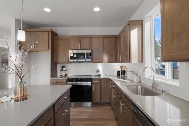 kitchen featuring appliances with stainless steel finishes, sink, hanging light fixtures, dark wood-type flooring, and a healthy amount of sunlight