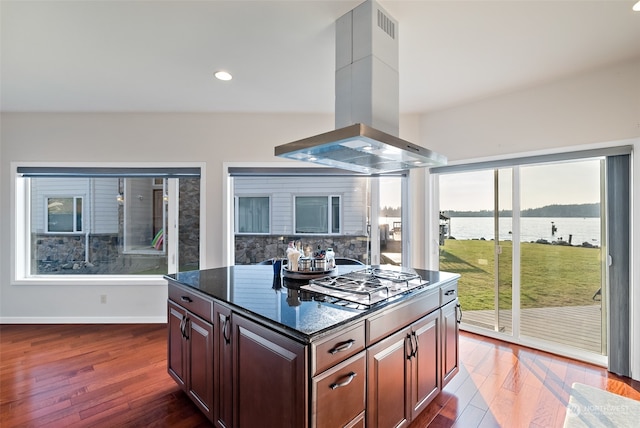 kitchen featuring a water view, stainless steel gas cooktop, tasteful backsplash, dark wood-type flooring, and island range hood