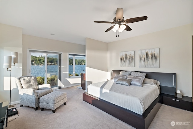 bedroom featuring a water view, ceiling fan, and light colored carpet