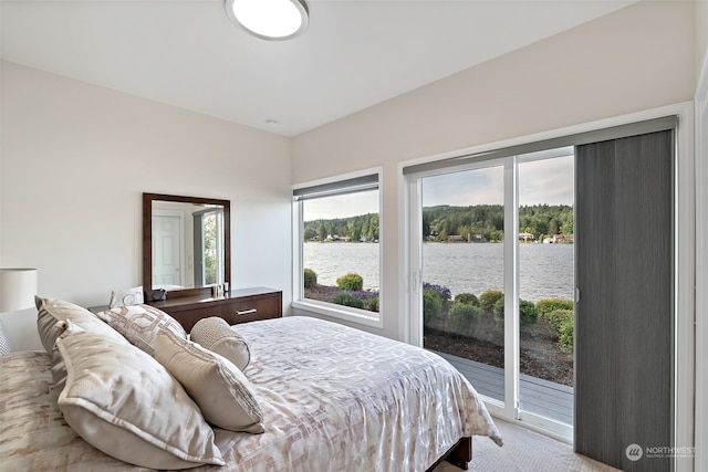 bedroom featuring a water view, access to outside, and light carpet