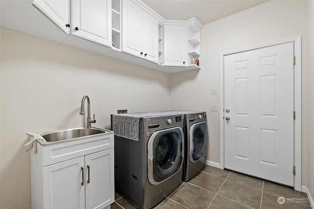 clothes washing area with independent washer and dryer, cabinets, sink, and dark tile patterned flooring