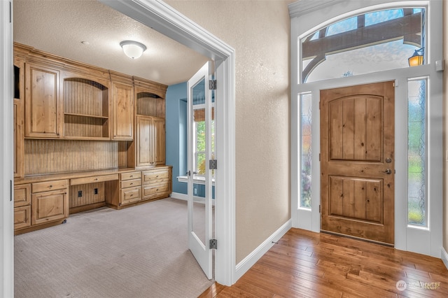 entryway featuring light hardwood / wood-style floors, a textured ceiling, and built in desk