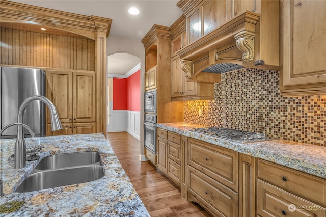 kitchen featuring light stone countertops, appliances with stainless steel finishes, sink, light hardwood / wood-style floors, and crown molding