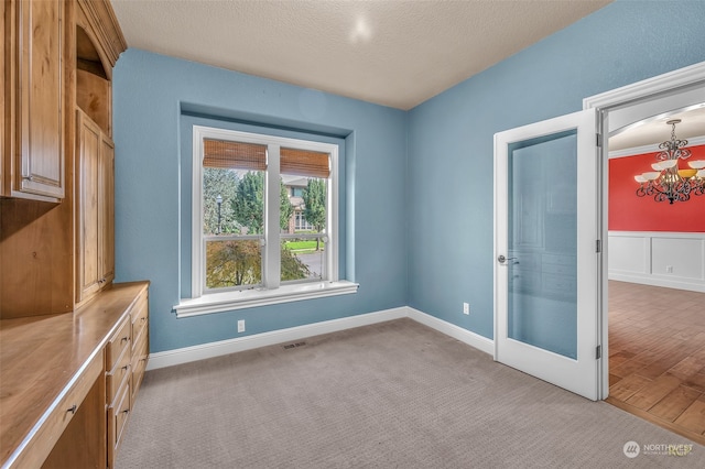 spare room featuring light wood-type flooring, a textured ceiling, and a chandelier