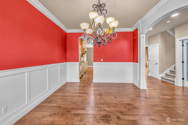 unfurnished dining area featuring ornamental molding, an inviting chandelier, and hardwood / wood-style floors