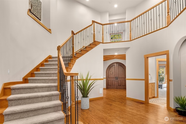 stairway with a high ceiling and hardwood / wood-style flooring