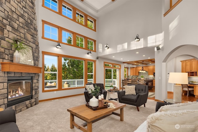 carpeted living room featuring a high ceiling, a fireplace, and a wealth of natural light