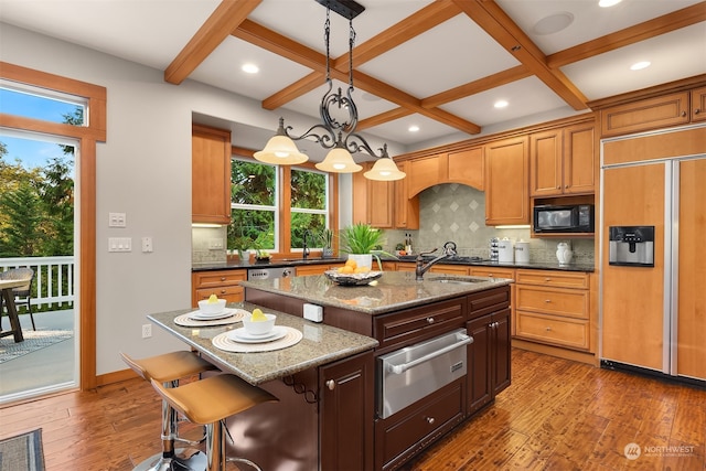 kitchen featuring built in appliances, plenty of natural light, a kitchen island with sink, and wood-type flooring