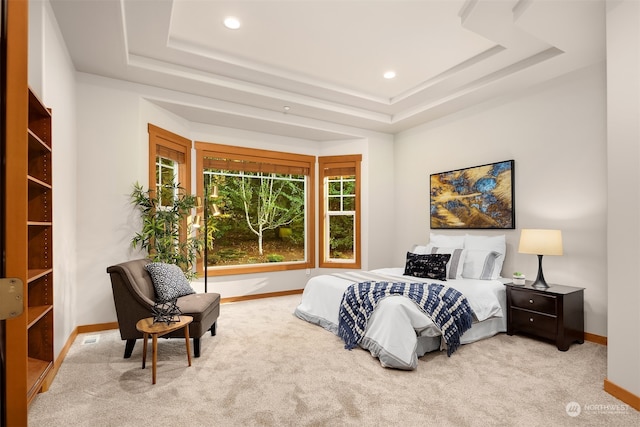 bedroom with a tray ceiling and light colored carpet