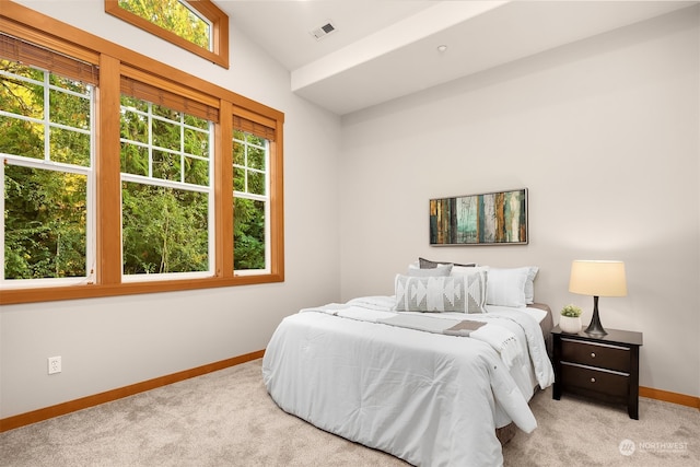 bedroom featuring lofted ceiling, light colored carpet, and multiple windows