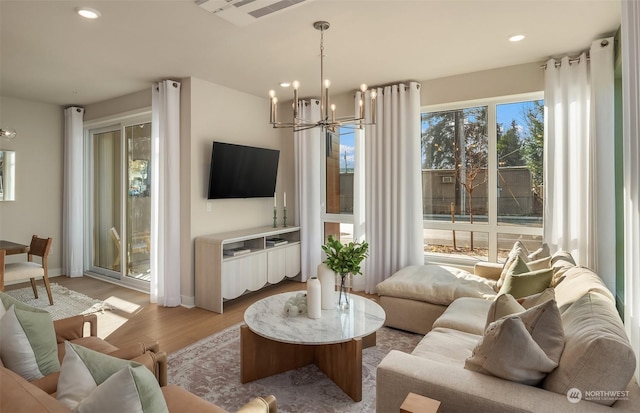 living room with a notable chandelier, plenty of natural light, and light wood-type flooring